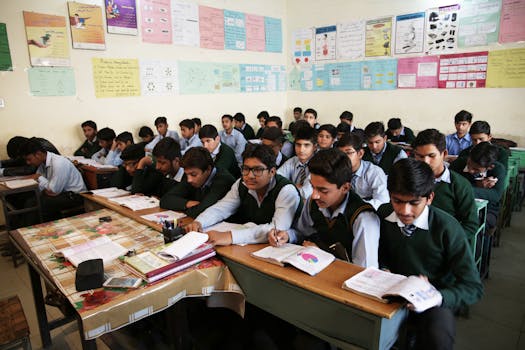 High school boys attentively listening and taking notes in a crowded classroom.